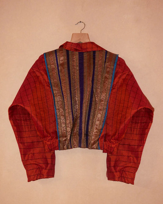 AMBR is our one-of-a-kind cropped two-toned silk brocade bomber jacket, handcrafted by skilled artisans in-house using a vintage silk saris. The back panel features a rich brocade. In our effort to use what already exists, both layers are crafted entirely from vintage textiles. With an exaggerated collar, a slight cinch at the waist, and antique buttons, Ambr stands as a tribute to local craftsmanship and mindful creation.