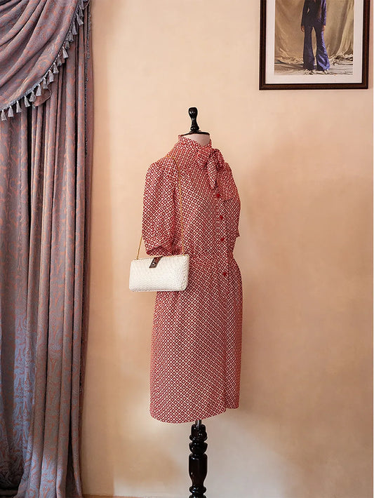 70s vintage Nina Ricci red dress with geometric print, puff sleeves, front buttons, and self-tie neck detail — elegant and easy daywear silhouette.