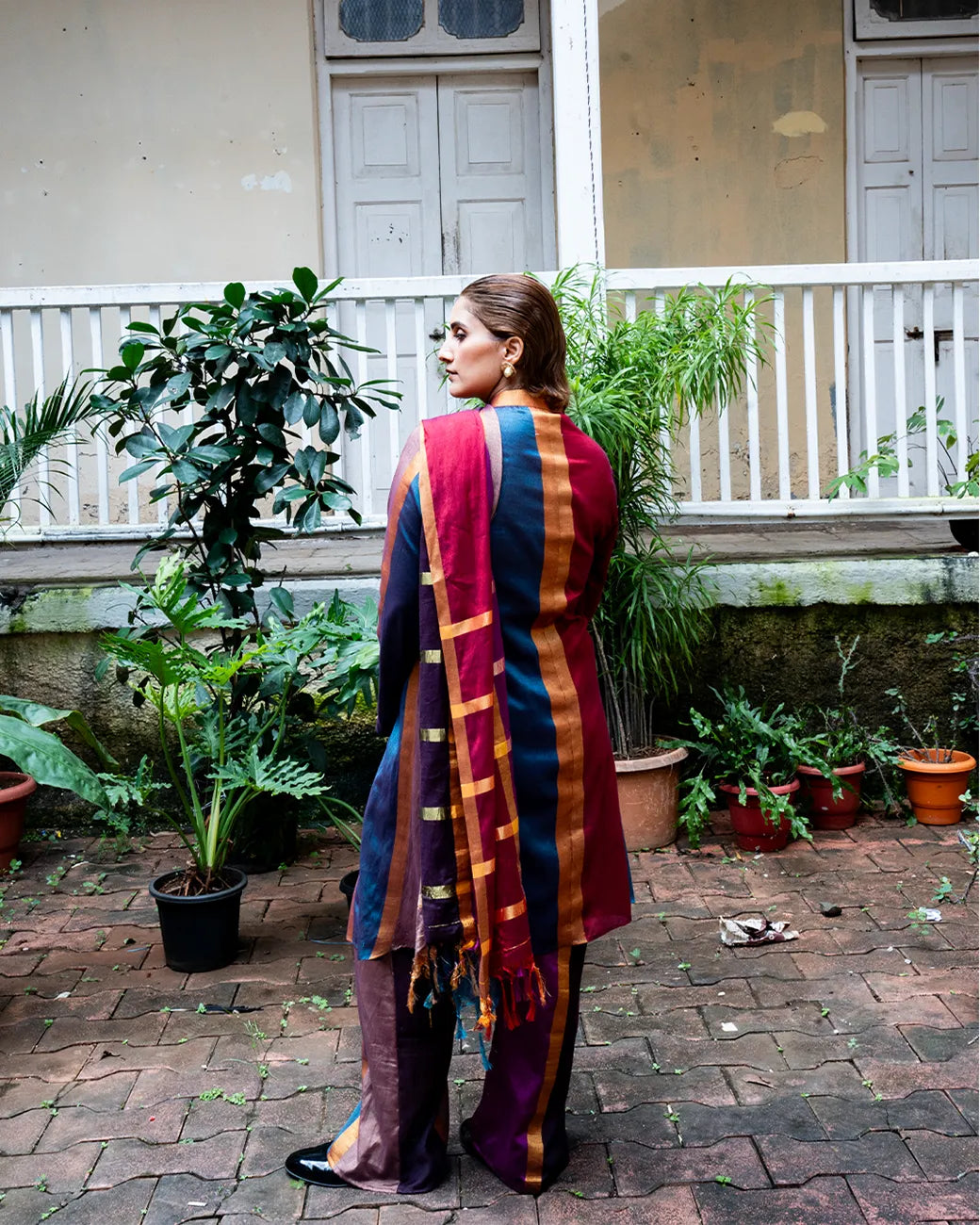 Drapa set with sari-inspired trench and dupatta detail in earthy jewel tones with gold accents.