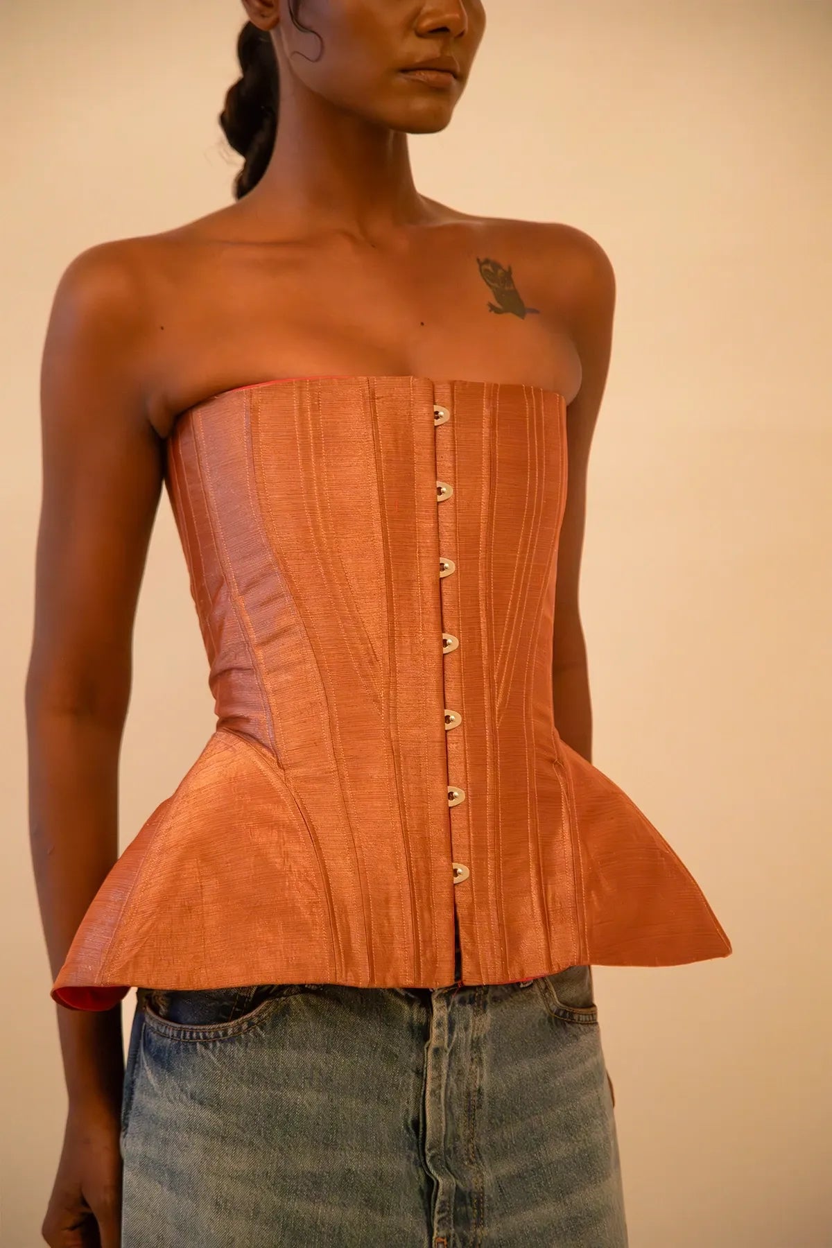 Bell corset handcrafted from a vintage rose gold silk sari, featuring front closure and adjustable lace-up back, designed for a structured fit and celebrating mindful craftsmanship.
